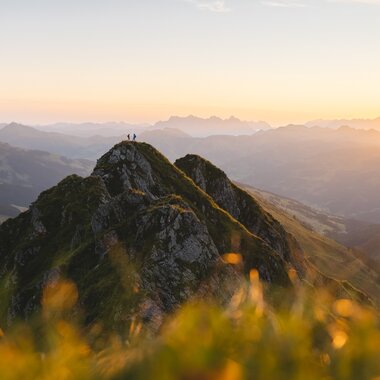 Berggipfel bei Sonnenaufgang in den Alpen, Nebelmeer und Sonnenstrahlen über dem Tal
