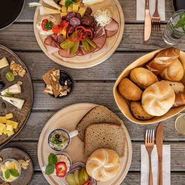 Liebevoll angerichtete Tiroler Jause mit Käse Wurst Brot und regionalen Spezialitäten auf einem Holztisch in der Region St Johann in Tirol