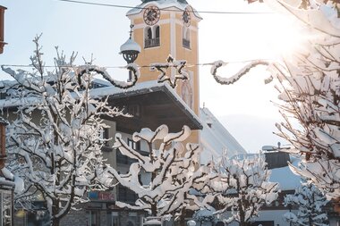 Die Pfarrkirche von Westendorf steht umgeben von Schnee und winterlicher Atmosphäre im Ortszentrum.